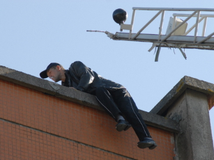 Gerą valandą ant stogo krašto balansavusiam Dmitrijui gelbėtojai turėjo atnešti ir parūkyti. / Sigito Grinčinaičio nuotrauka.